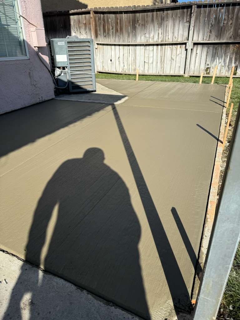 Freshly finished concrete side-yard slab with clean broom finish and edge forms.