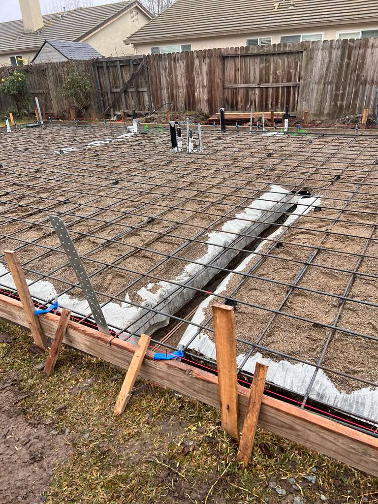 Foundation pad with full rebar grid, formwork, and plumbing rough-ins ready for pour.