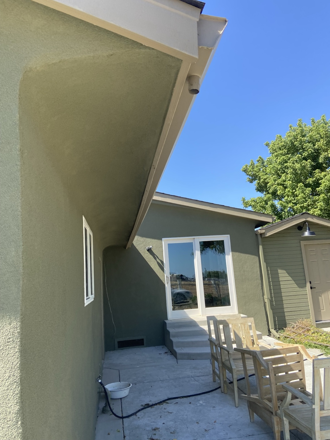 Finished green exterior renovation with patio and sliding door.