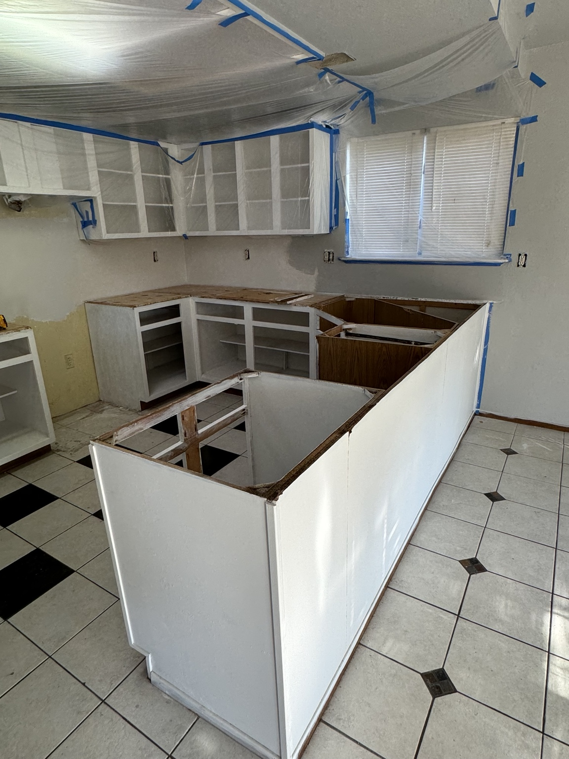 Kitchen demolition and in-progress remodel with covered cabinets.